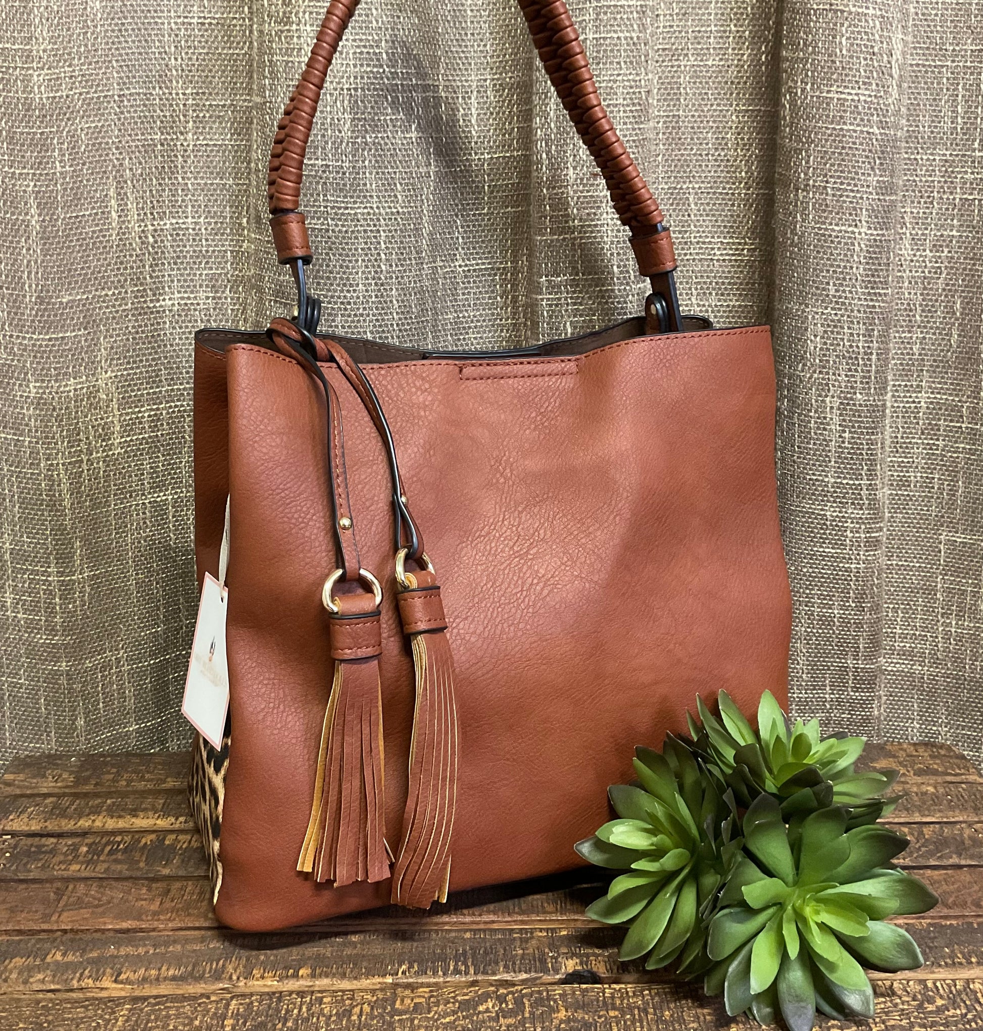 Tomball Leopard Contrast Bag in warm brown vegan leather with bold leopard-print sides, braided handle, and removable tassels – versatile, stylish handbag for day-to-night wear.