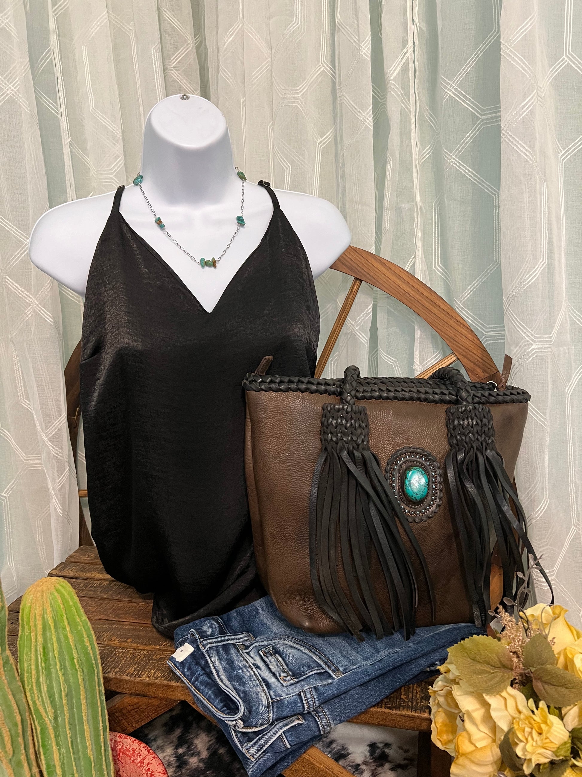American Darling full-grain leather tote with leather fringe and a turquoise stone accent on the front. Approximately 11" (H) x 14" (W) x 5" (D).