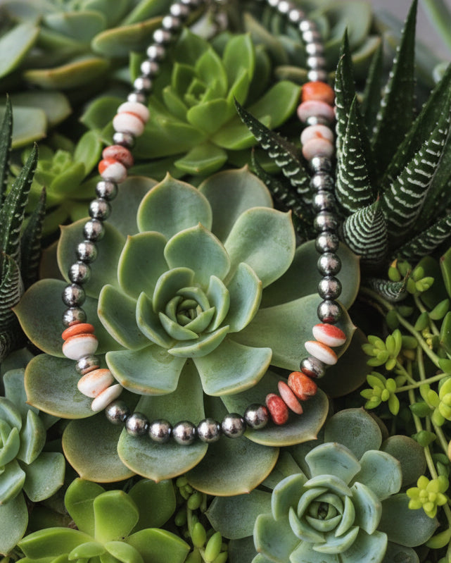 Sterling silver pearl necklace with 8mm beads and orange spiny oyster accents, shown styled flat to highlight natural color variation and polished sterling finish.