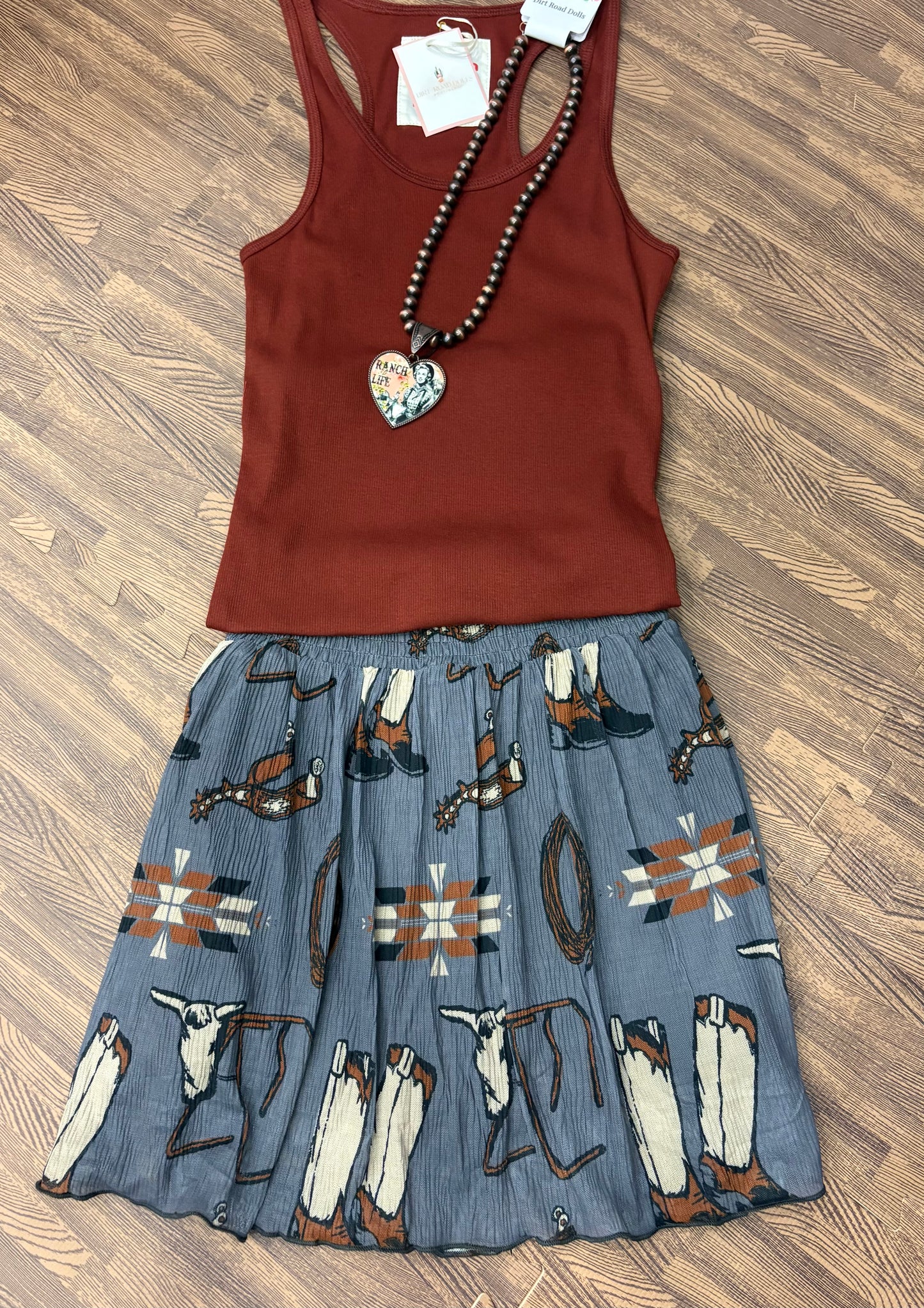 Grey flowy skort with built-in shorts featuring western-themed print of boots, spurs, ropes, and Aztec motifs