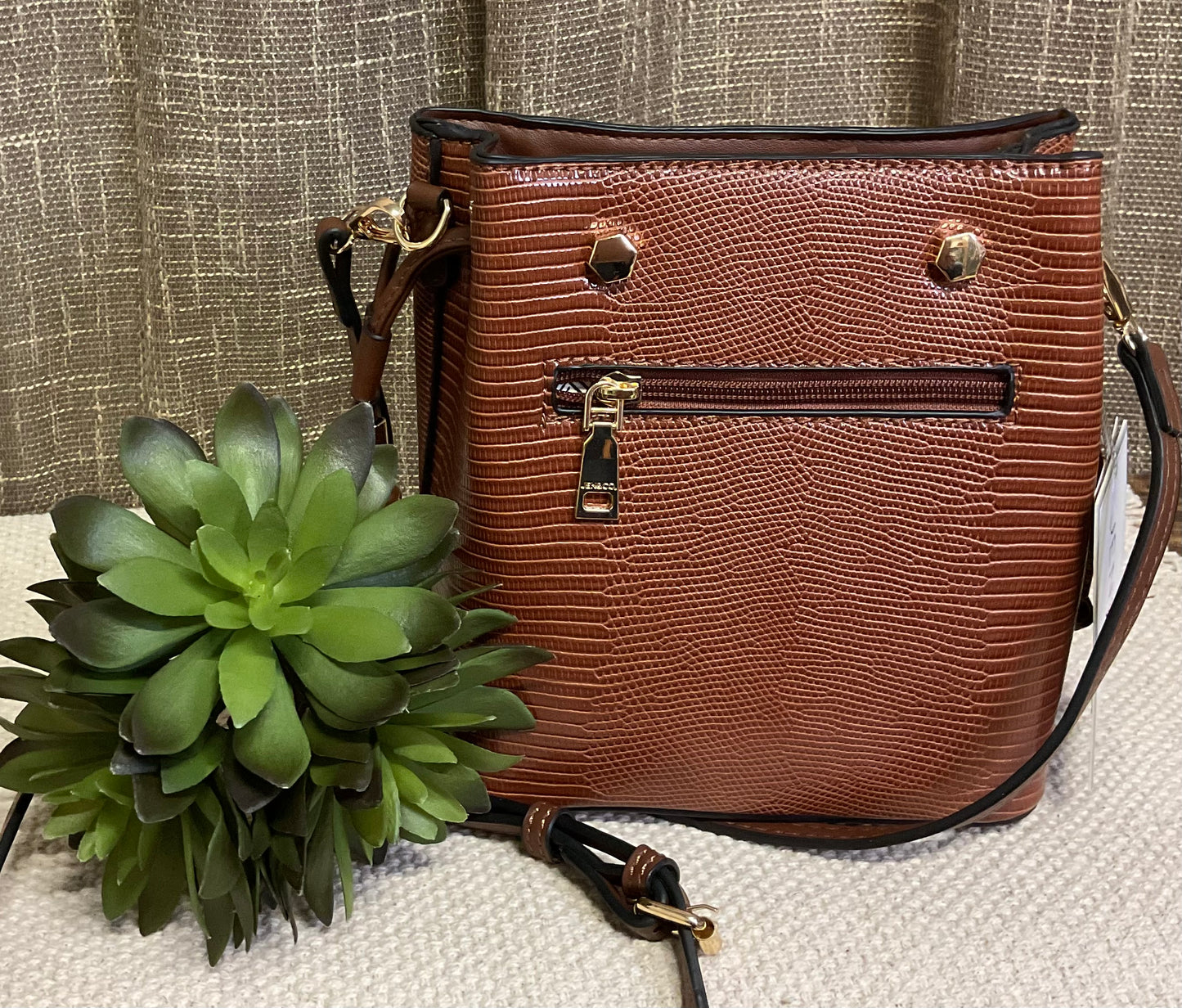 Marion Bucket Bag in high-quality vegan leather with adjustable strap, gold-toned hardware, and side drawstring – available in rich brown lizard print or bold red for versatile, stylish everyday use.