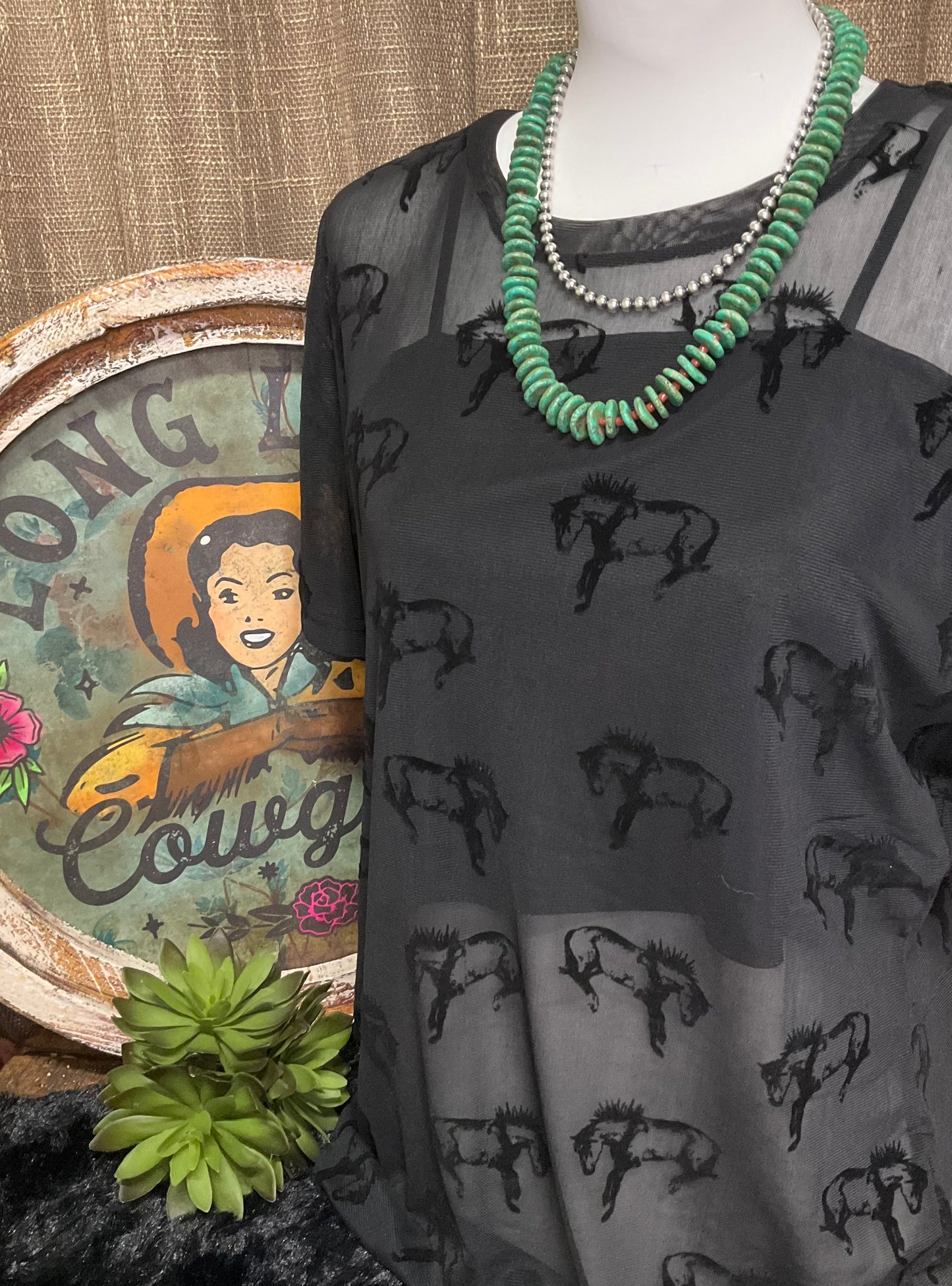 Close-up image of the Buck Off Mesh Tee showcasing a bold bucking horse pattern on a short-sleeve, stretchy fabric design, paired with an included cami for a complete, edgy look.