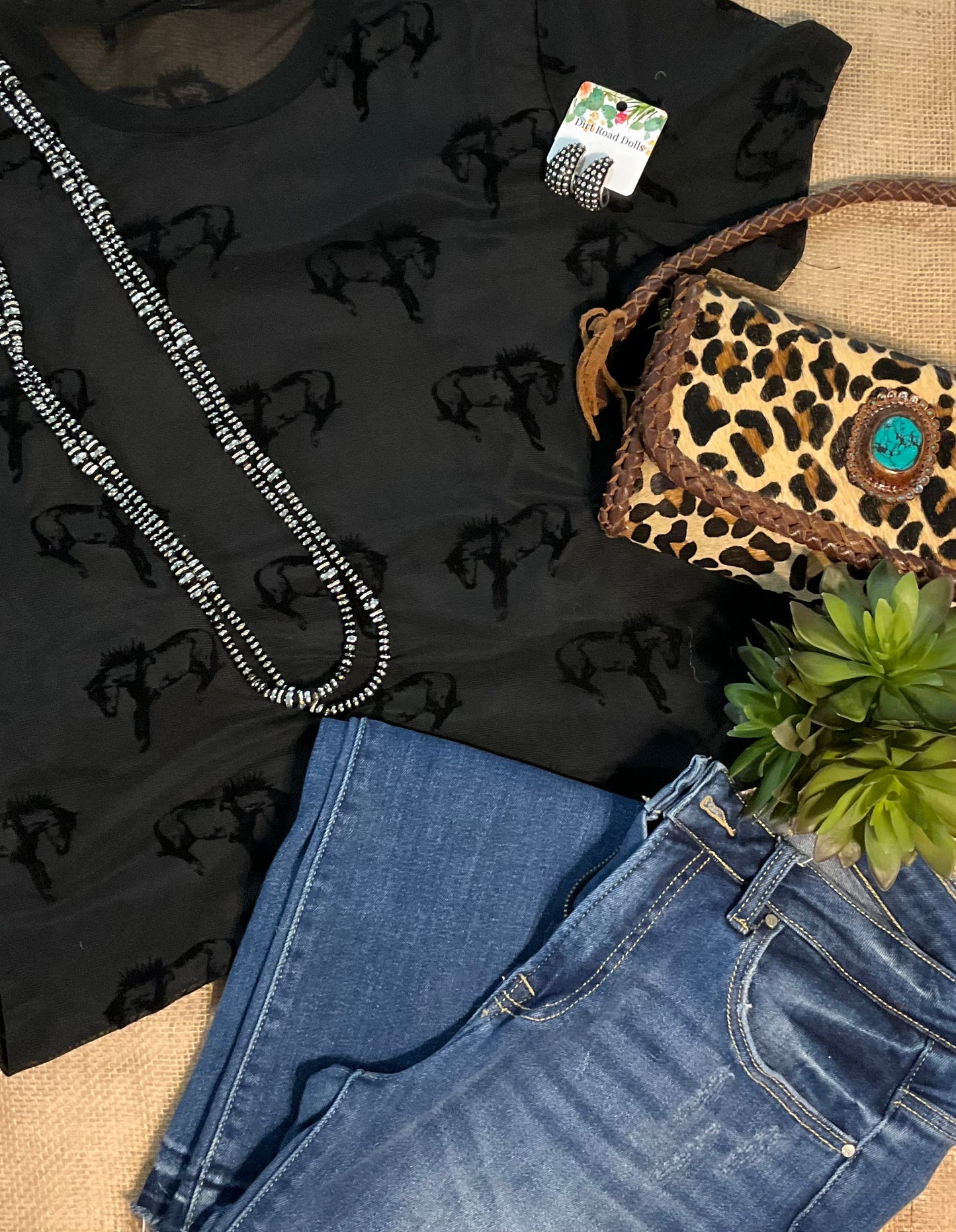 Close-up image of the Buck Off Mesh Tee showcasing a bold bucking horse pattern on a short-sleeve, stretchy fabric design, paired with an included cami for a complete, edgy look.