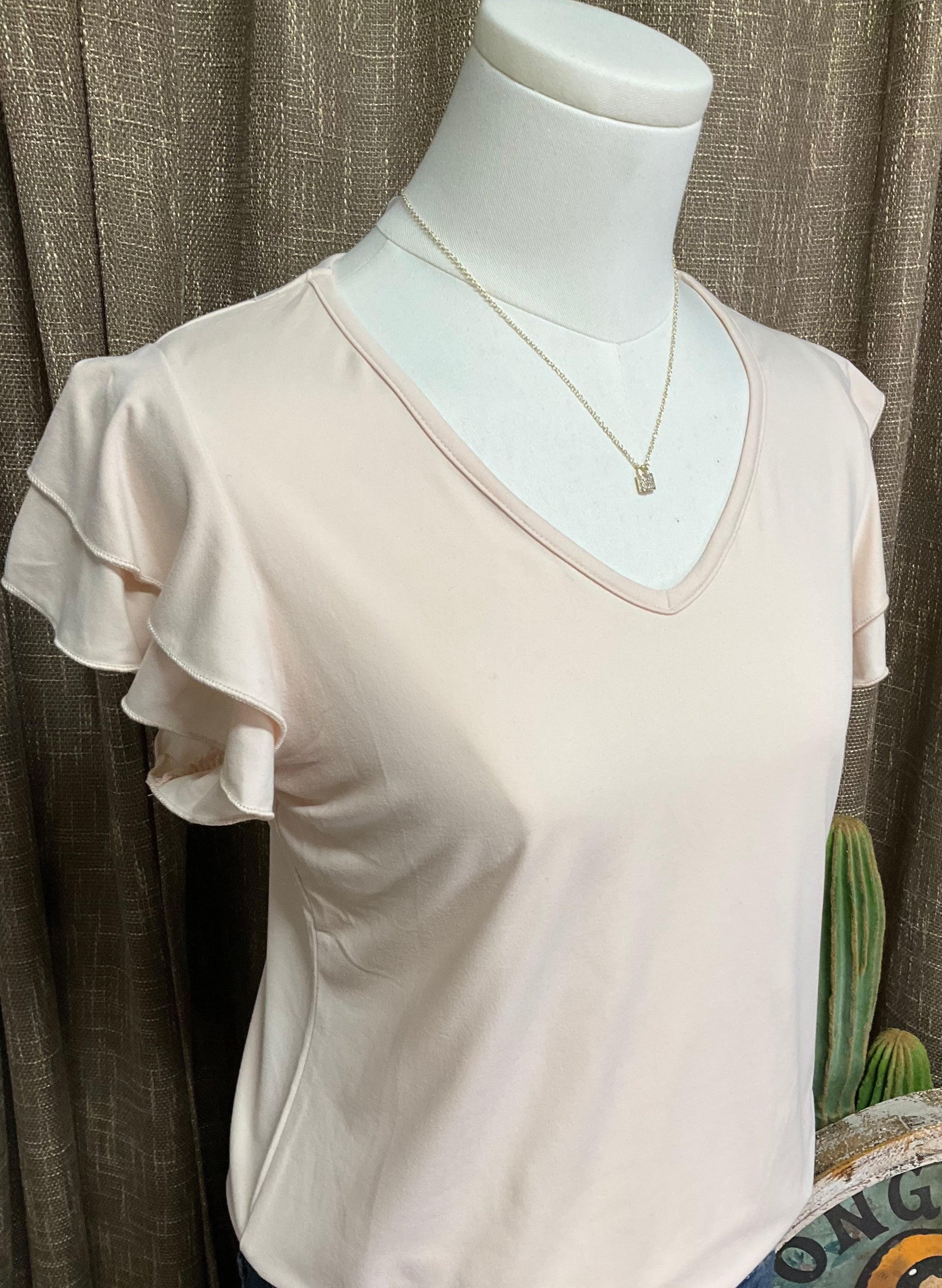 Image of the cream-colored Elaine Ruffle Top featuring a flattering V-neckline and delicate ruffle sleeves, crafted from luxuriously soft fabric for an effortlessly elegant look