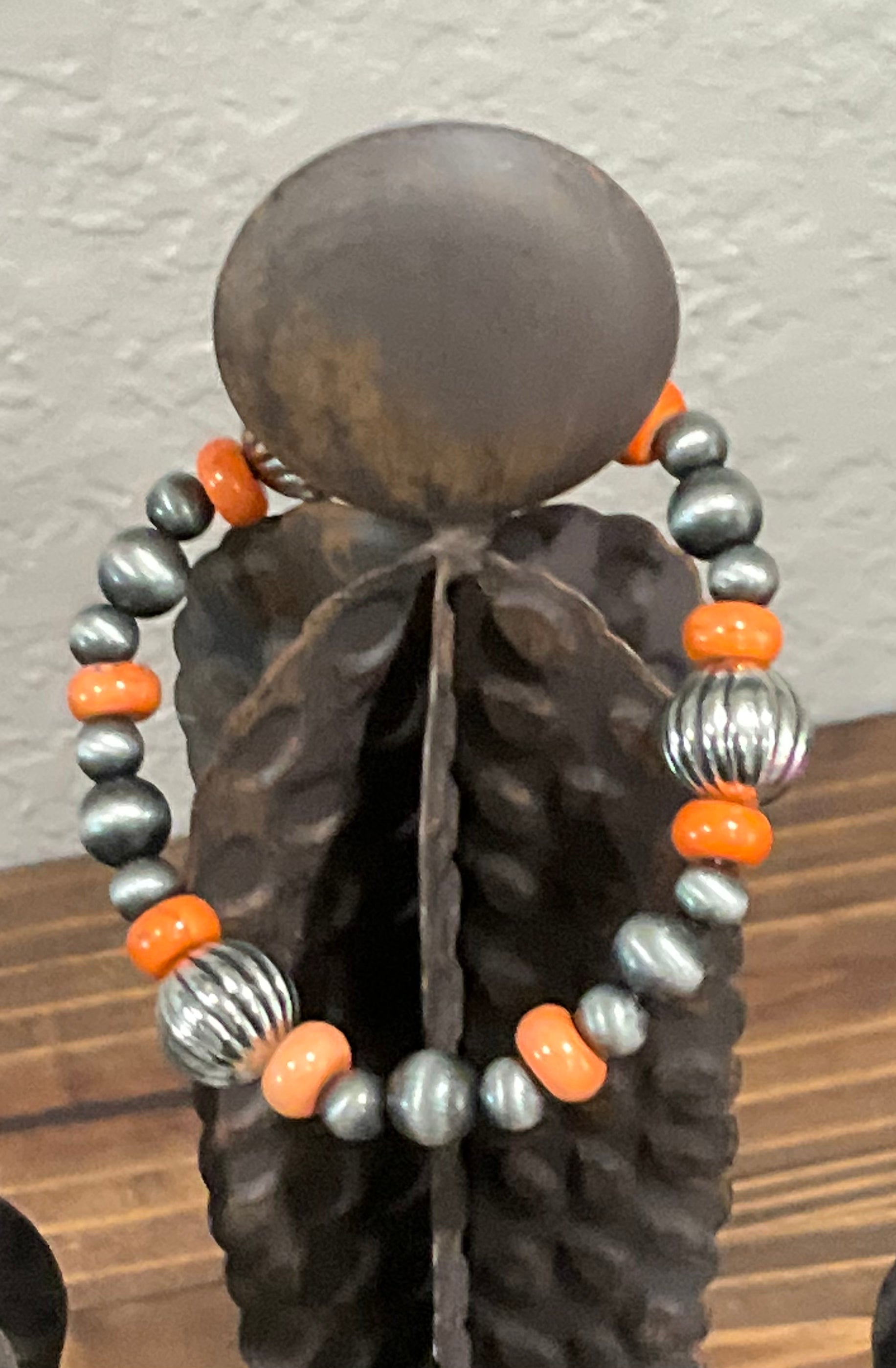 The Desert Drift Stretch Bracelet featuring a mix of warm faux silver and rich orange stone beads, styled on a neutral background with rustic, earthy textures.