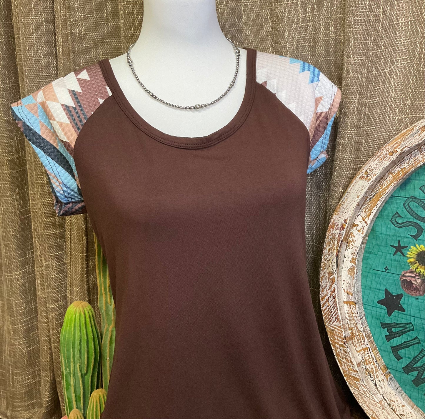 Carmen Aztec Sleeve Top featuring a soft, solid body with vibrant Aztec-patterned sleeves, adding a bold and colorful touch to your look.