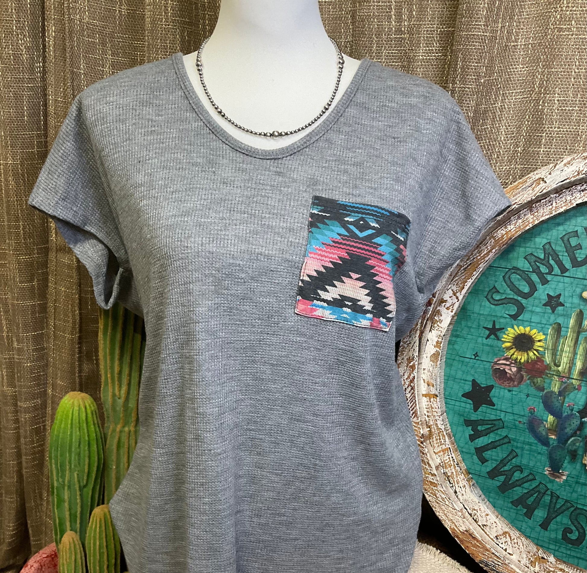 Sasha Top in a cozy waffle knit fabric with a short sleeve silhouette, scoop neckline, and rounded hem. Features an Aztec-inspired chest pocket for a pop of southwestern style. Available in ivory or heather grey.