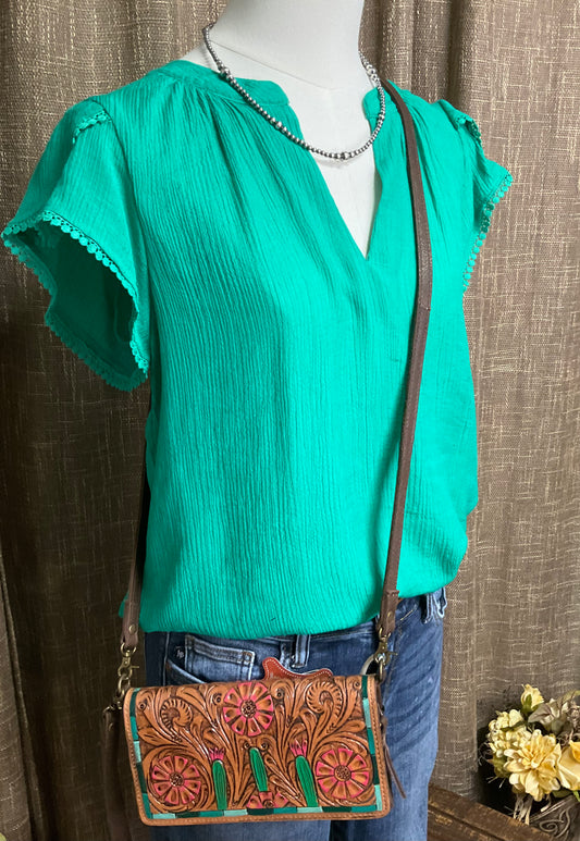 Hanna Blouse featuring a split V-neck, short petal sleeves, and delicate lace trim. Crafted from a lightweight blend of rayon, nylon, and polyester, offering a soft, flowing silhouette. Not lined.