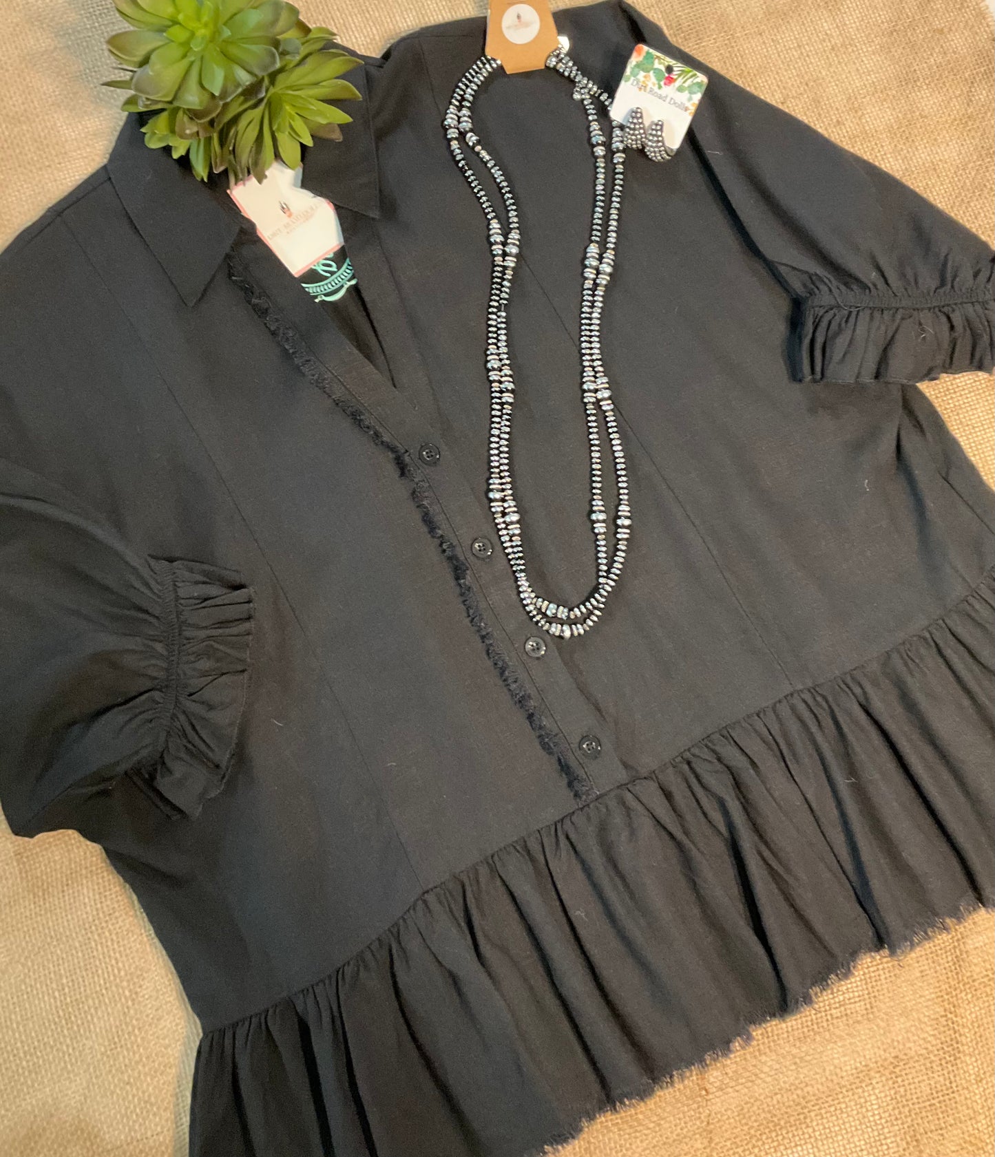 Harlie Linen Top in a lightweight, breathable linen fabric featuring a button-up front, 3/4 sleeves, and a ruffled bottom hem with frayed edging for a relaxed yet chic look. Designed for versatile styling across seasons.