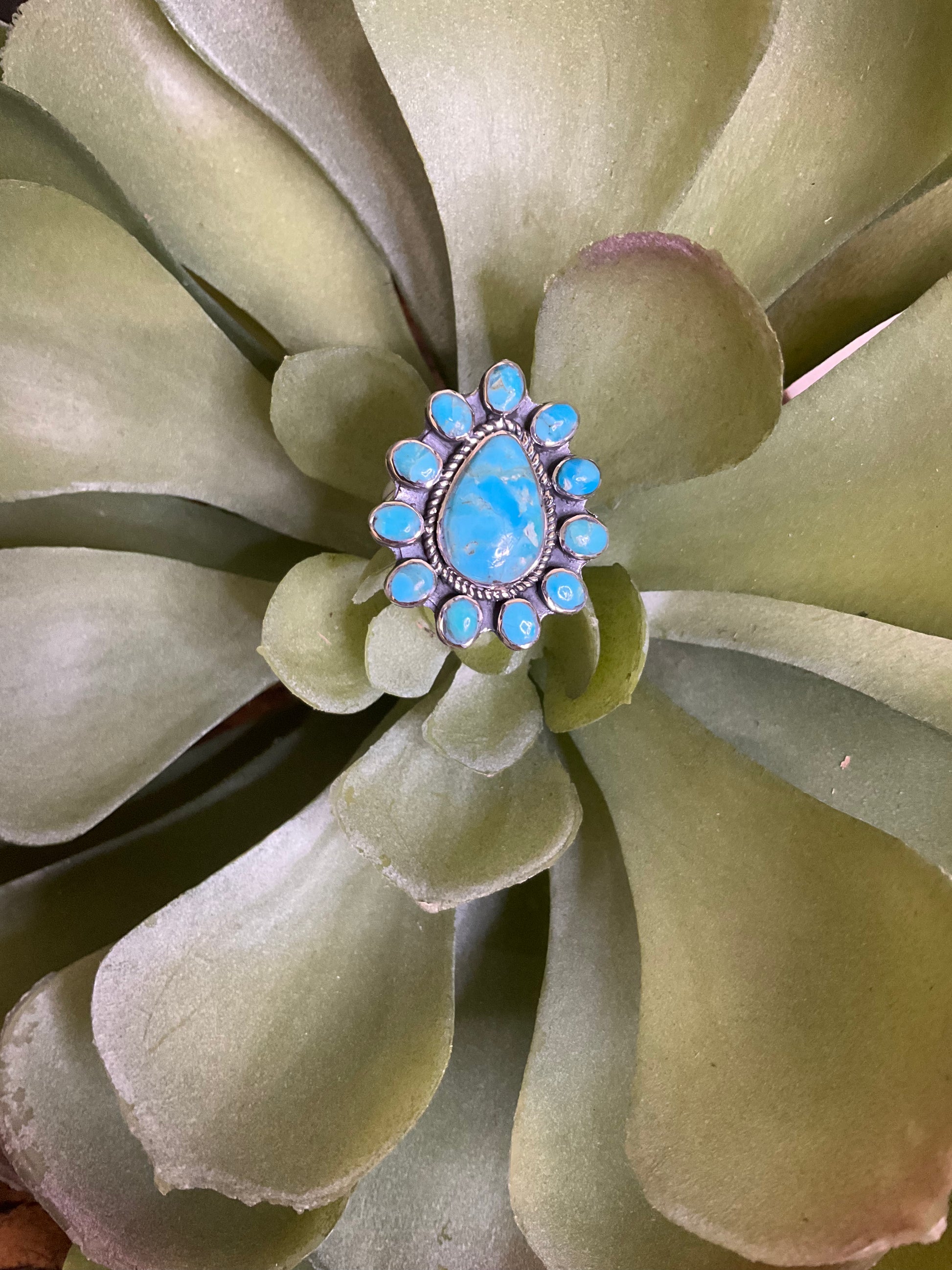 Minot Sterling & Turquoise Ring with a large teardrop turquoise center stone and surrounding oval turquoise stones set in sterling silver