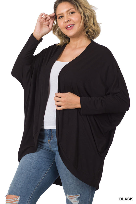 Model wearing a relaxed-fit cocoon wrap cardigan with a soft, draped silhouette. Lightweight, stretchy knit fabric shown layered over a tee and jeans for a cozy, casual outfit.