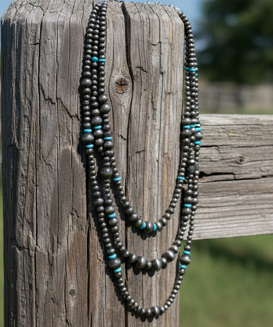 Triple strand silver-tone beaded necklace with turquoise-colored rondelle accents and layered western style.