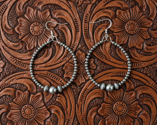 Sterling silver hoop earrings with 3mm pearls, an 8mm center pearl, and saucer accents, shown on french hooks with a lightweight open design.