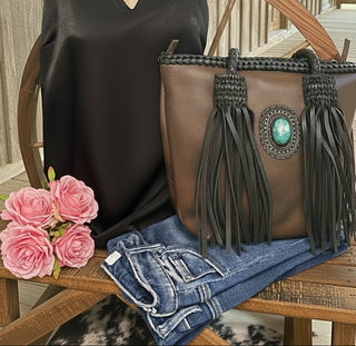American Darling full-grain leather tote with leather fringe and a turquoise stone accent on the front. Approximately 11" (H) x 14" (W) x 5" (D).