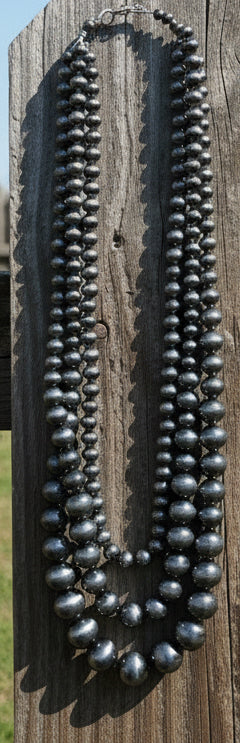 Triple strand silver-tone beaded necklace with graduated bead sizes and layered western style.