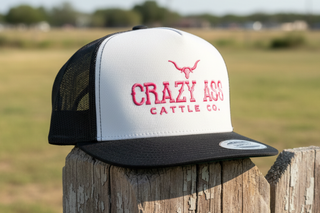 white trucker cap with black bill and pink lettering Crazy Ass Cattle Co ranch hat