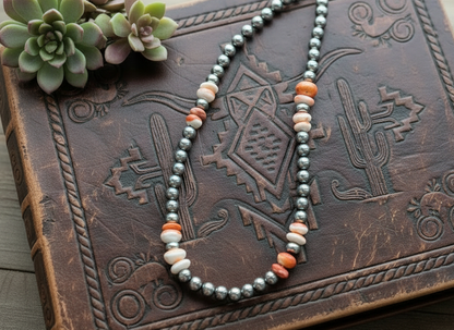 Sterling silver pearl necklace with 8mm beads and orange spiny oyster accents, shown styled flat to highlight natural color variation and polished sterling finish.