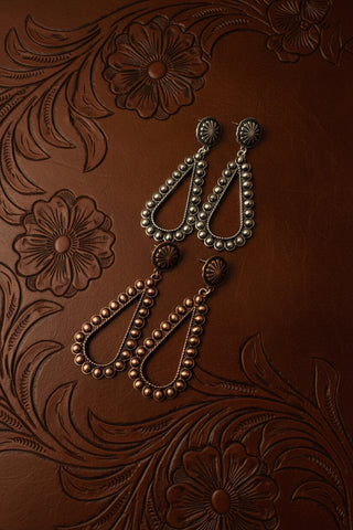 Boutique teardrop earrings with polished bead border and engraved concho tops