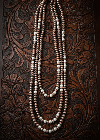 Copper toned layered necklace with faux pearl accents and triple strands