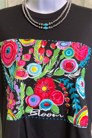 A black t-shirt with a vibrant floral graphic design in multiple colors, featuring the word 'Bloom' in the design.