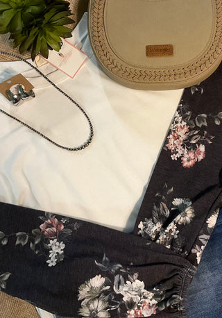 Image of the Alice Floral Top—a white top crafted from soft fabric featuring intricately designed floral sleeves in shades of charcoal and grey.