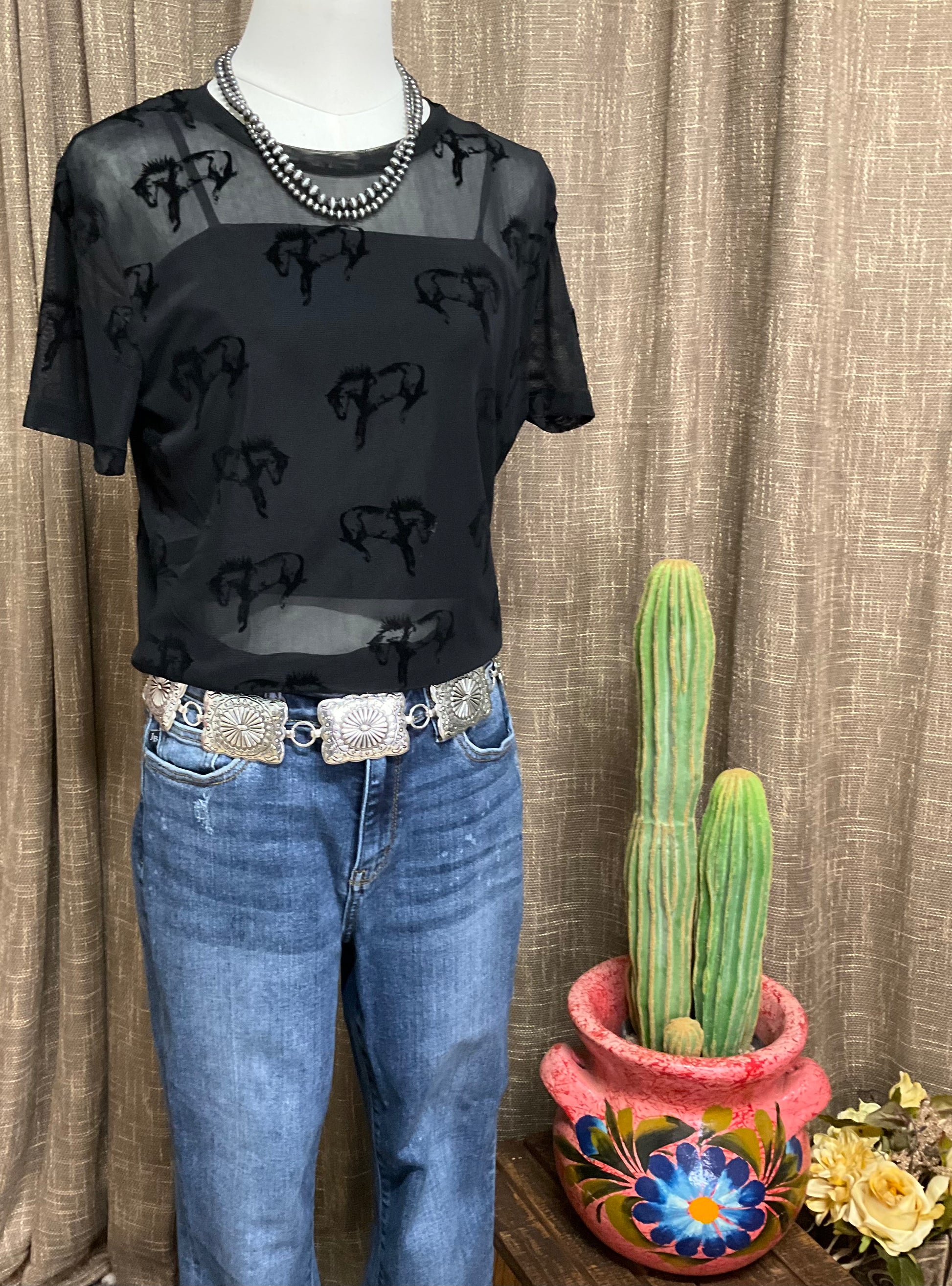 Close-up image of the Buck Off Mesh Tee showcasing a bold bucking horse pattern on a short-sleeve, stretchy fabric design, paired with an included cami for a complete, edgy look.