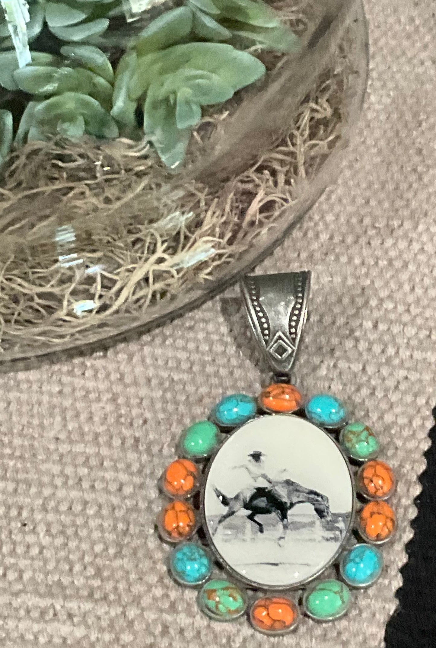 Vintage-inspired oval pendant featuring a bronc rider graphic, surrounded by turquoise or multicolored stones