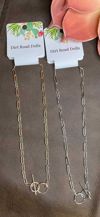 Two chokers, one gold-toned and one silver-toned, with a paperclip chain design and toggle closures, displayed on a card.