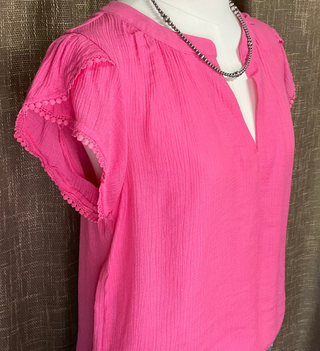 Hanna Blouse featuring a split V-neck, short petal sleeves, and delicate lace trim. Crafted from a lightweight blend of rayon, nylon, and polyester, offering a soft, flowing silhouette. Not lined.