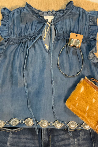 Jenna Chambray Blouse in soft blue lyocell—sleeveless top with high neckline, feminine neck tie, keyhole front detail, ruffle trim, and gently ruched yoke for subtle texture and charm.