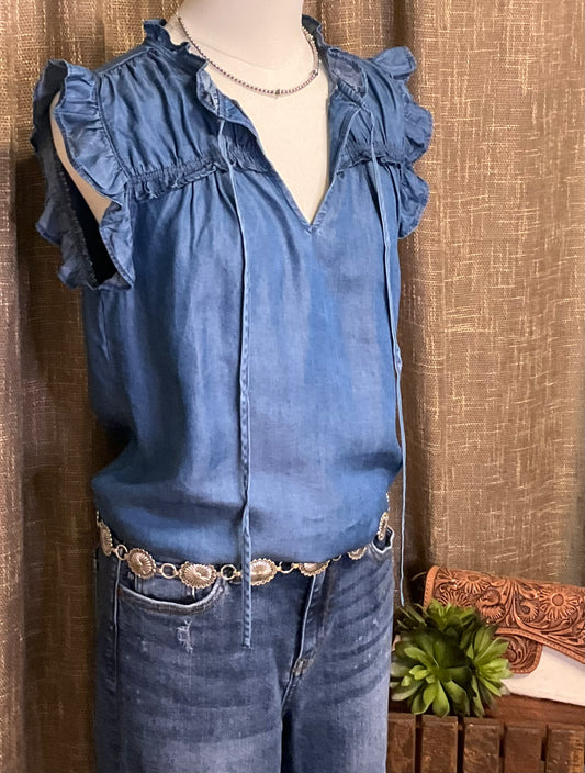 Jenna Chambray Blouse in soft blue lyocell—sleeveless top with high neckline, feminine neck tie, keyhole front detail, ruffle trim, and gently ruched yoke for subtle texture and charm.