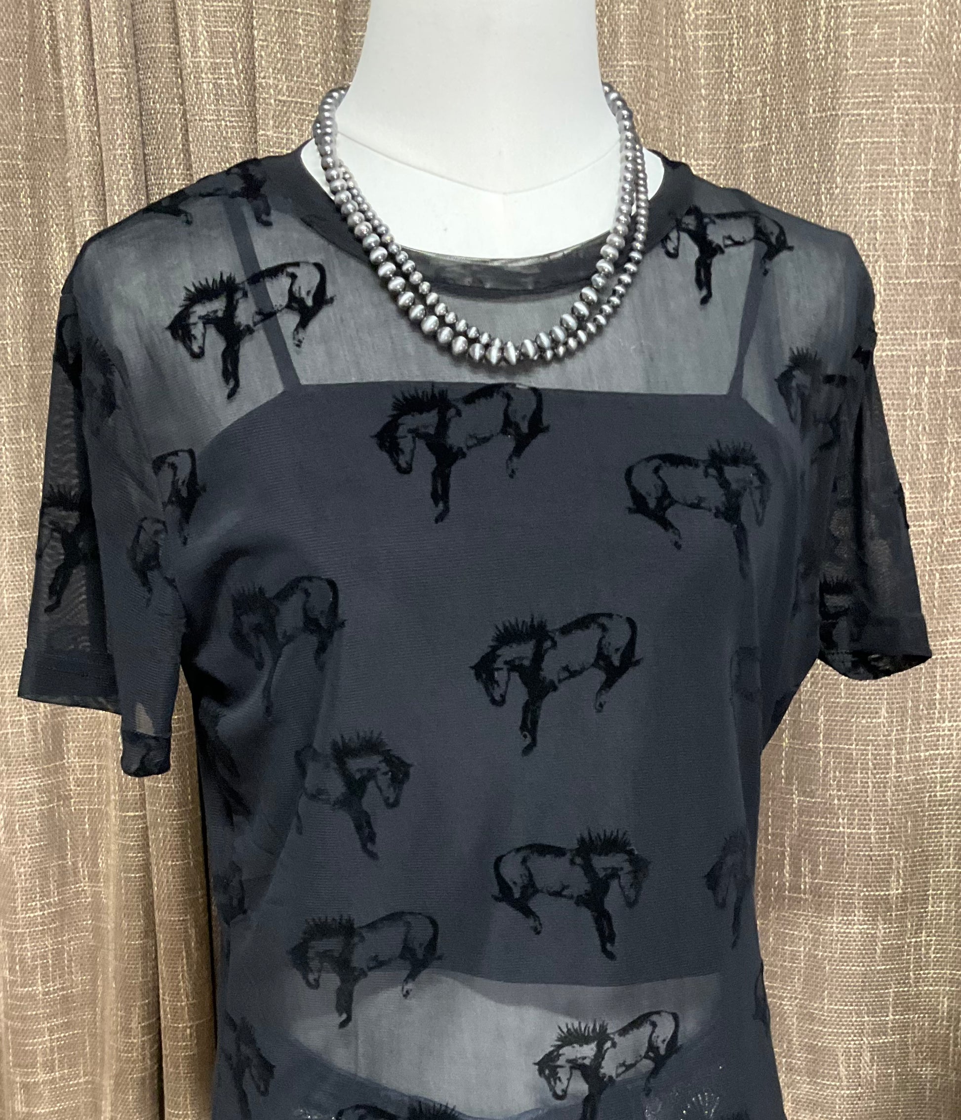 Close-up image of the Buck Off Mesh Tee showcasing a bold bucking horse pattern on a short-sleeve, stretchy fabric design, paired with an included cami for a complete, edgy look.