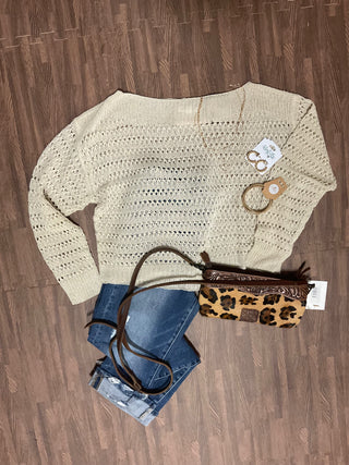 Women's crochet knit sweater layered with denim and leopard crossbody bag