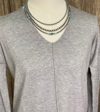 Women’s neutral v-neck sweater with exposed front seam and split hem in oatmeal and grey