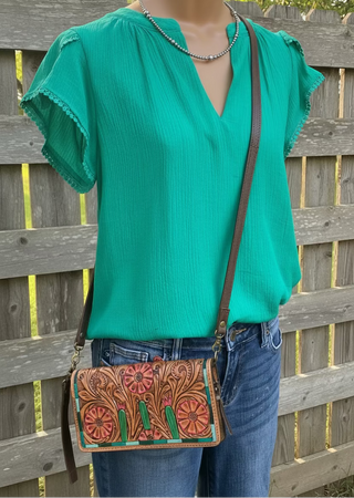 Hanna Blouse featuring a split V-neck, short petal sleeves, and delicate lace trim. Crafted from a lightweight blend of rayon, nylon, and polyester, offering a soft, flowing silhouette. Not lined.