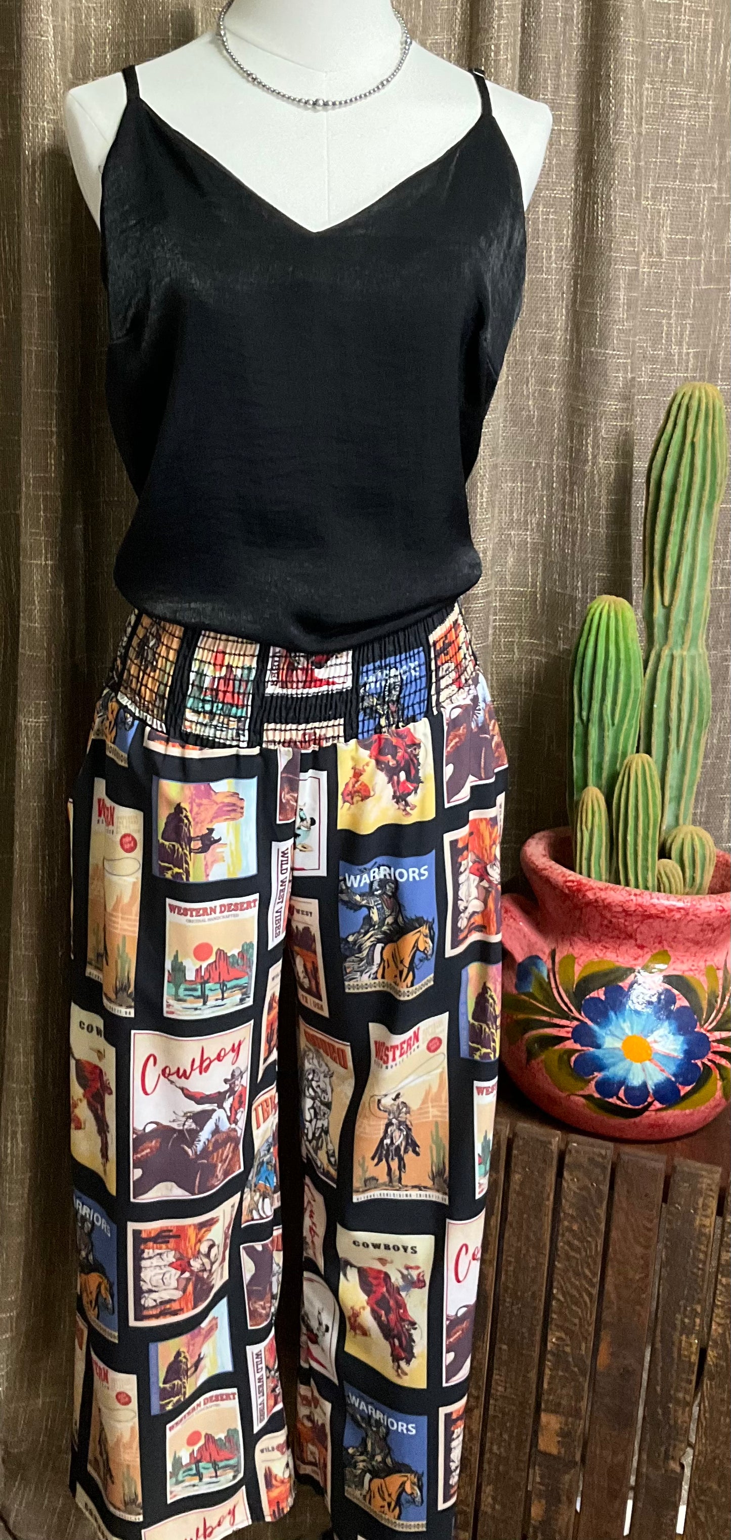 Black palazzo pants with vintage western graphics, featuring a smocked elastic waist. The pants have a wide-leg flowy fit