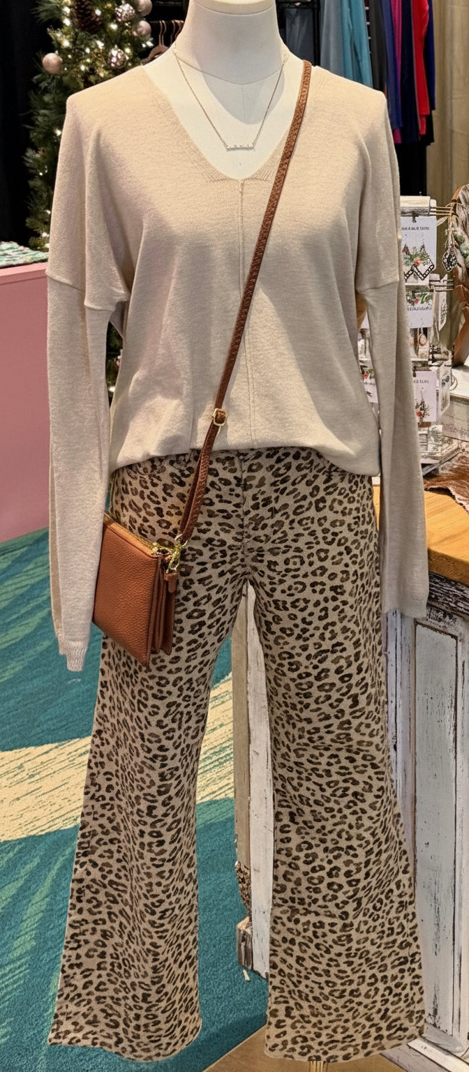 Risen Lisa cheetah print mid-rise slim straight jeans in neutral tones, ankle-length stretch denim for women.  Shown on mannequin with tan sweater and brown crossbody