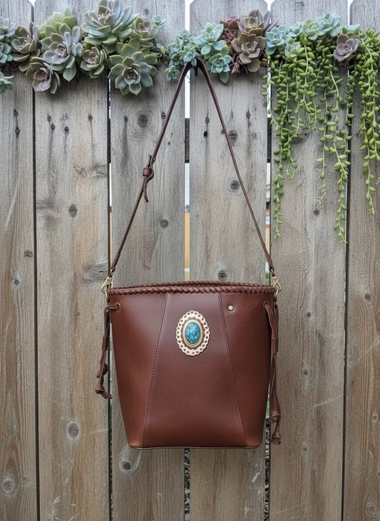 Full grain leather bucket bag with braided detailing and turquoise stone accent by American Darling