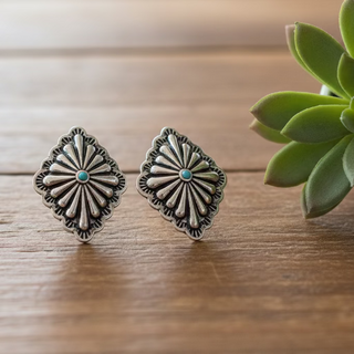 Silver-tone western concho stud earrings with engraved detail and a small turquoise-style center stone.