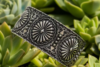 Wide western-style cuff bracelet with engraved concho designs, available in silver tone and copper tone.