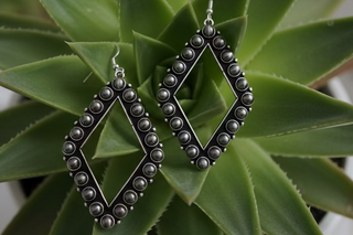 Open diamond-shaped earrings lined with round burnished silver toned beads on a silver-tone frame with French hooks.