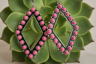 Open diamond-shaped earrings lined with round pink beads on a silver-tone frame with French hooks.