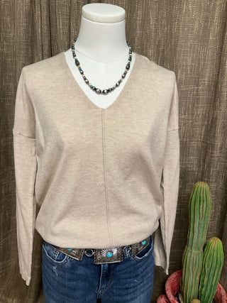 Women’s neutral v-neck sweater with exposed front seam and split hem in oatmeal and grey
