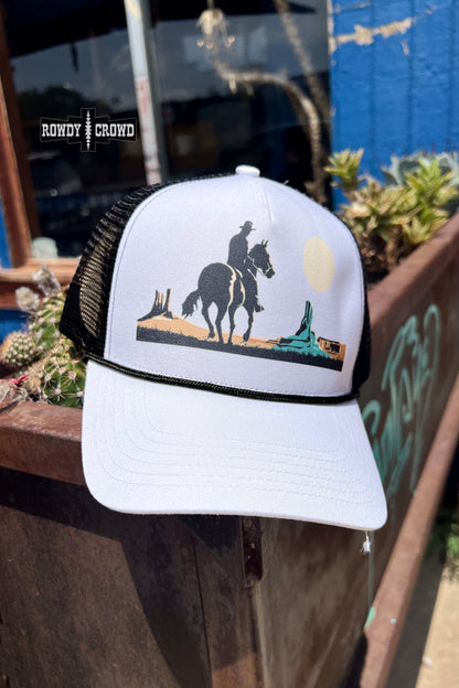 white and black trucker cap with horseback cowboy in desert scene