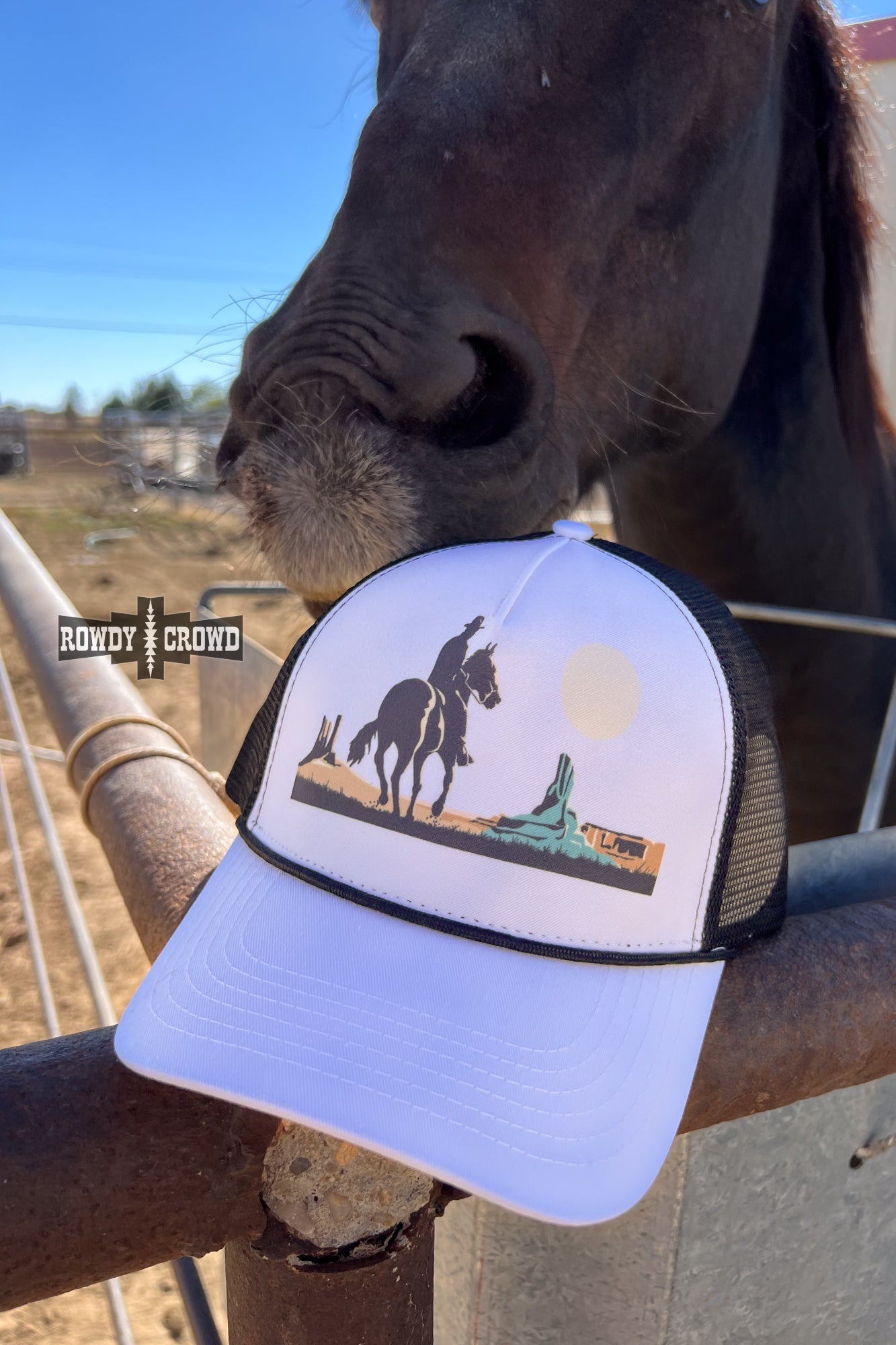 white and black trucker cap with horseback cowboy in desert scene