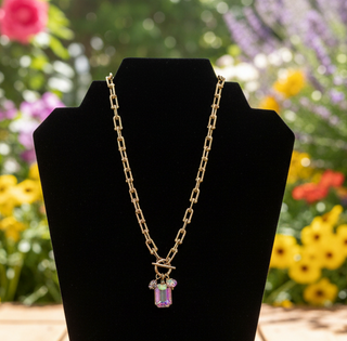 Gold charm necklace featuring emerald cut crystal and coin charm
