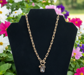 Gold charm necklace featuring emerald cut crystal and coin charm