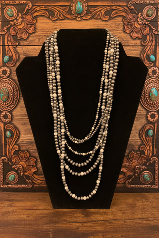 Layered western necklace featuring six strands of beads and faux pearls in silver tone or copper tone