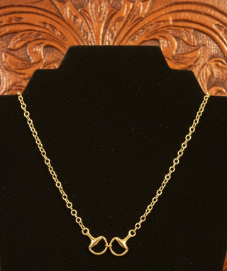 Gold horse bit necklace with adjustable chain on black jewelry display