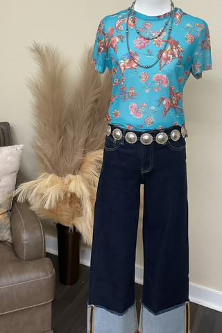 Women's turquoise western mesh top featuring colorful bucking horses and floral artwork.